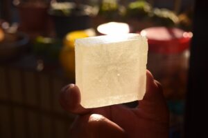Durchsichtige Seife, die von drei Fingern ins Licht gehalten wird