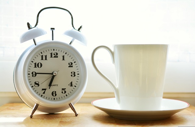 Alarm clock showing 6:45 am and a white coffe cup